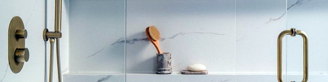 Marble shower wall with brushed brass valve and door pull