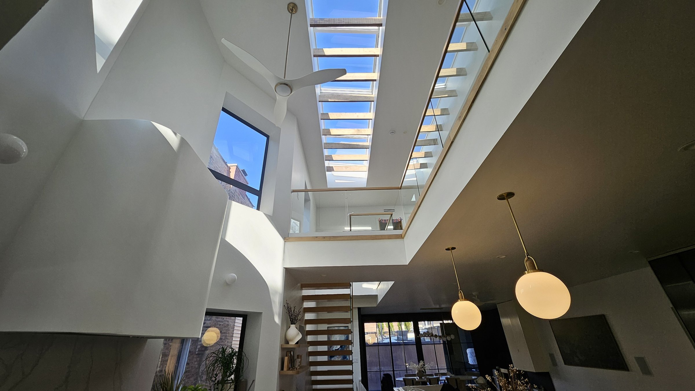 Floating oak stair and glass railings under a skylight